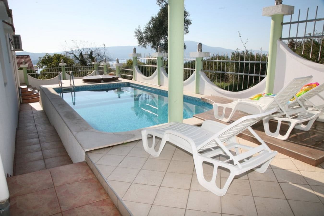 Pool mit Liegestühlen auf der Terrasse der Villa in Tivat, Montenegro, mit Panoramablick auf das Meer und die Berge.