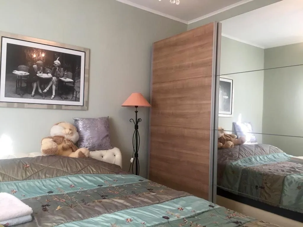 Bedroom with a bed, teddy bear, mirrored wardrobe, and floor lamp against the wall.