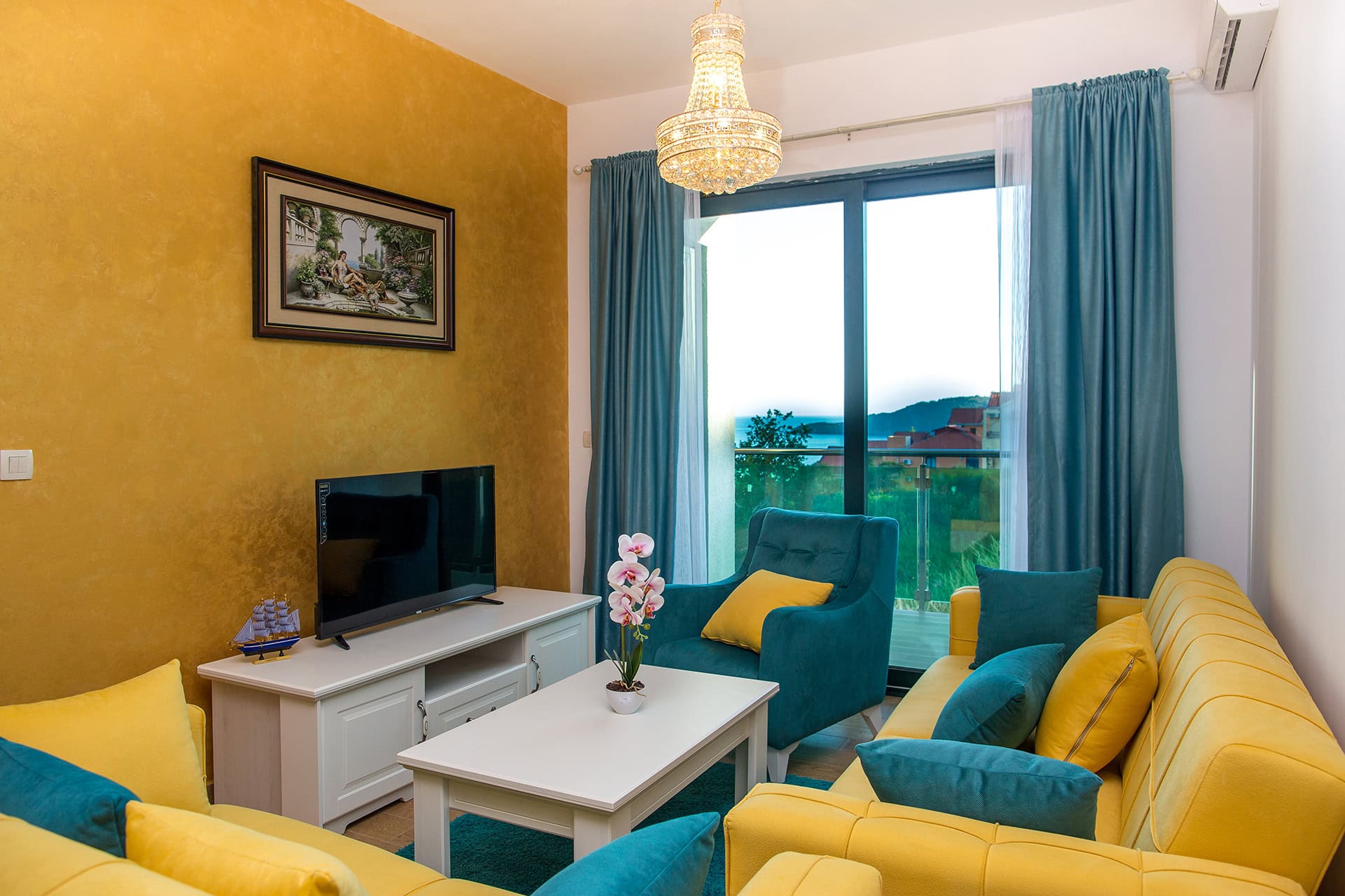 Wohnzimmer in einem Apartment in Bečići, Montenegro: gelb-blaues Interieur, Polstermöbel, TV und Panoramablick auf das Meer.