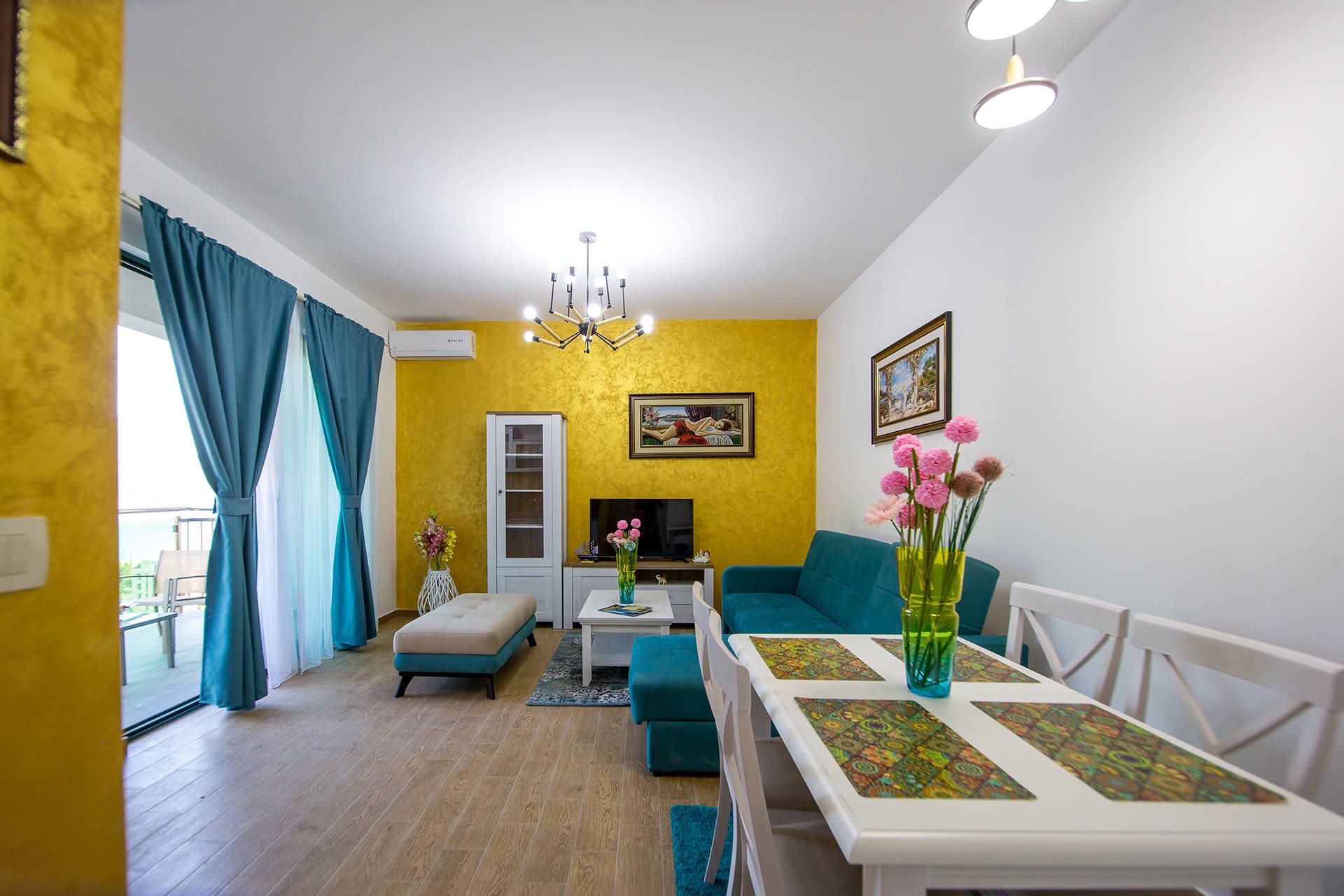 Wohnzimmer in einem Apartment in Bečići, Montenegro: Helles Interieur mit blauen Möbeln, gelben Wänden und Zugang zur Terrasse.