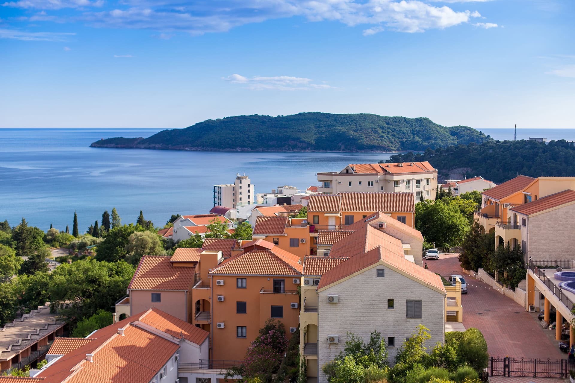 Panoramablick auf das Meer und eine Wohnanlage mit Ziegeldächern in Bečići, Montenegro.