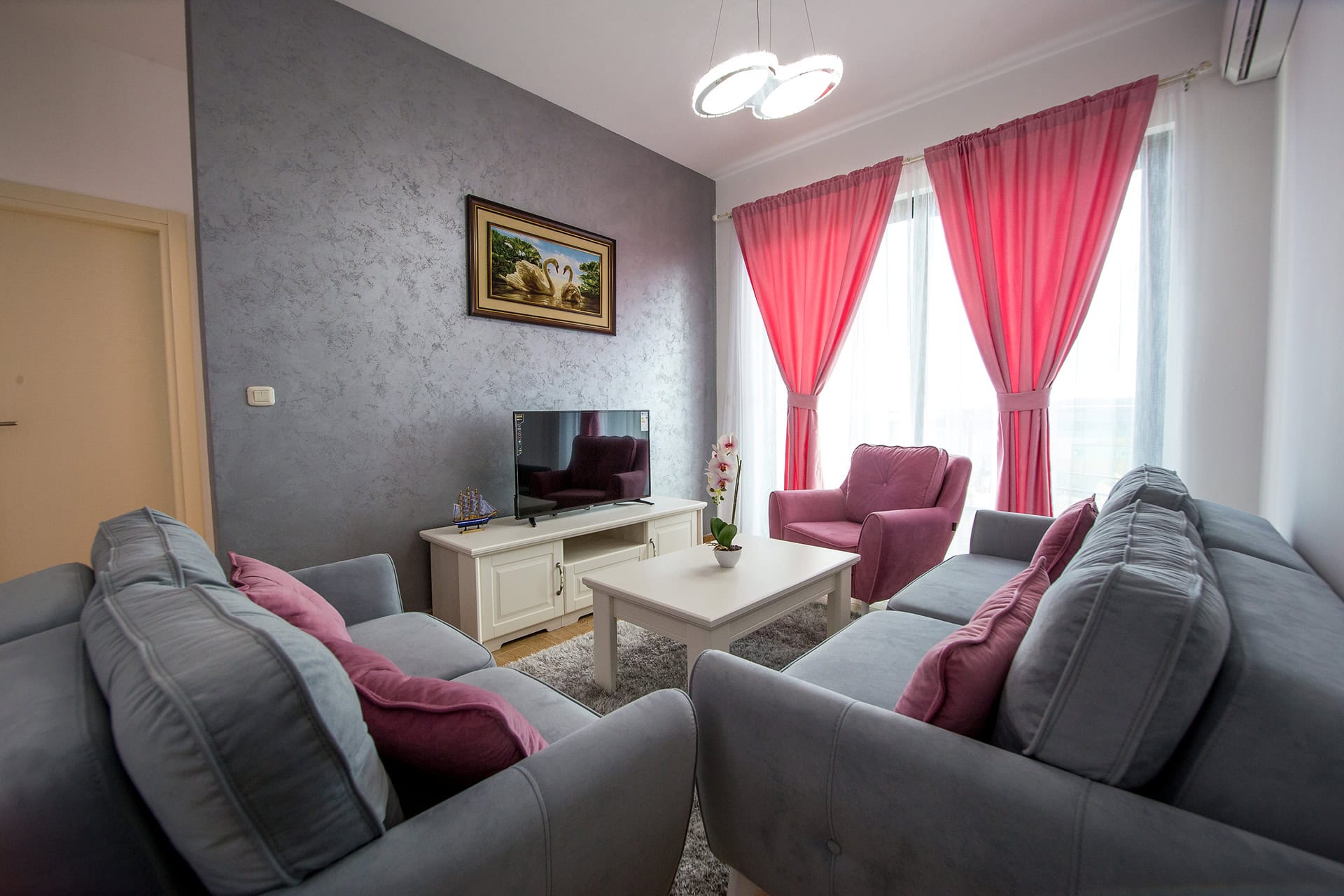 Gemütliches Wohnzimmer mit Polstermöbeln und grauen Wänden in einer zum Verkauf stehenden Wohnung in Bečići, Montenegro.