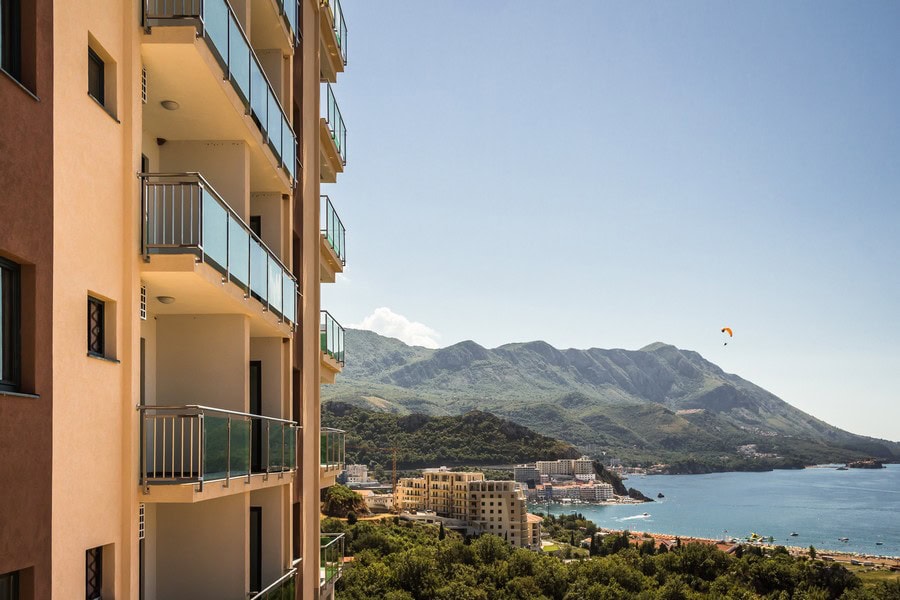 Moderner Wohnkomplex mit Balkonen in Bečići, Montenegro, mit Panoramablick auf das Meer und die Berge.