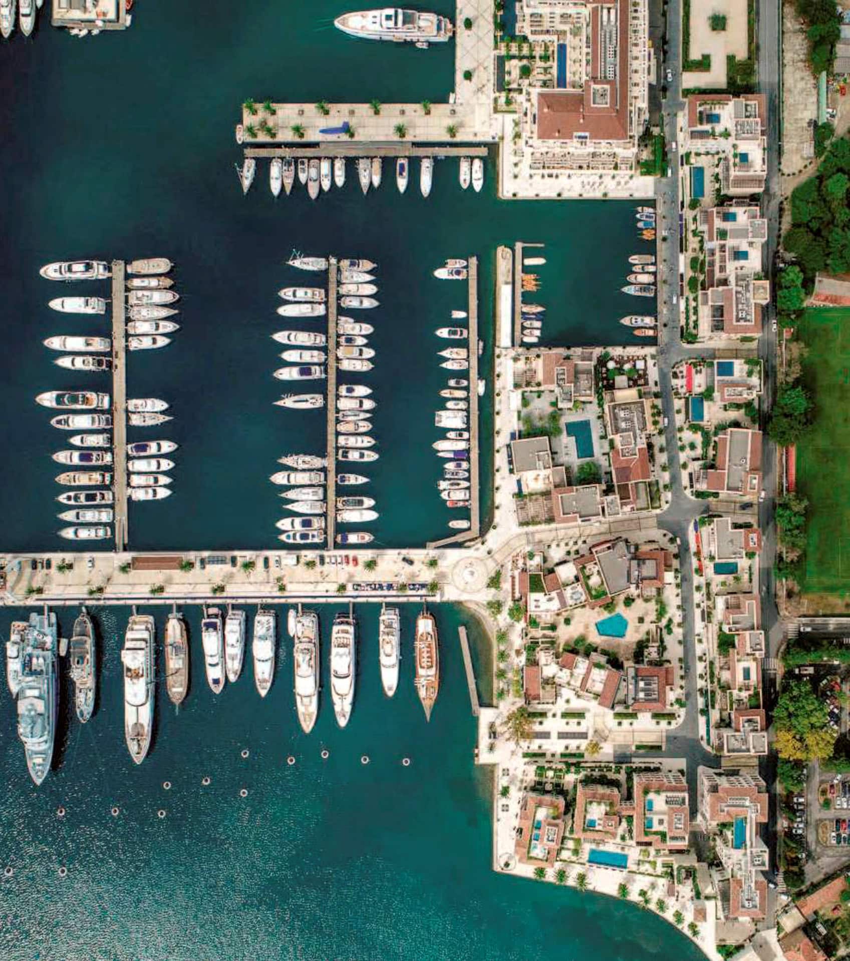 Pogled iz vazduha na marinu Porto Montenegro i hotel Boka Place u Tivtu, Crna Gora, sa usidrenim jahtama.