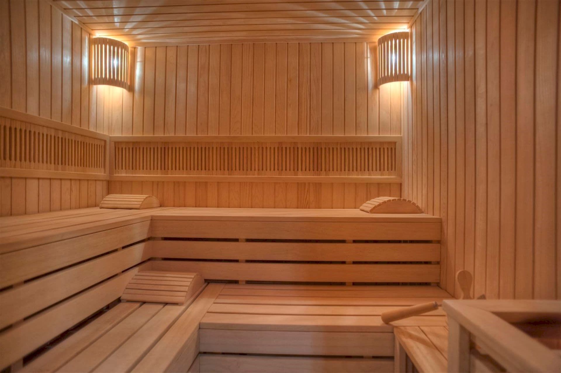 Sauna moderne en bois avec éclairage dans une villa à Krašići, Monténégro : finition en bois clair et bancs.