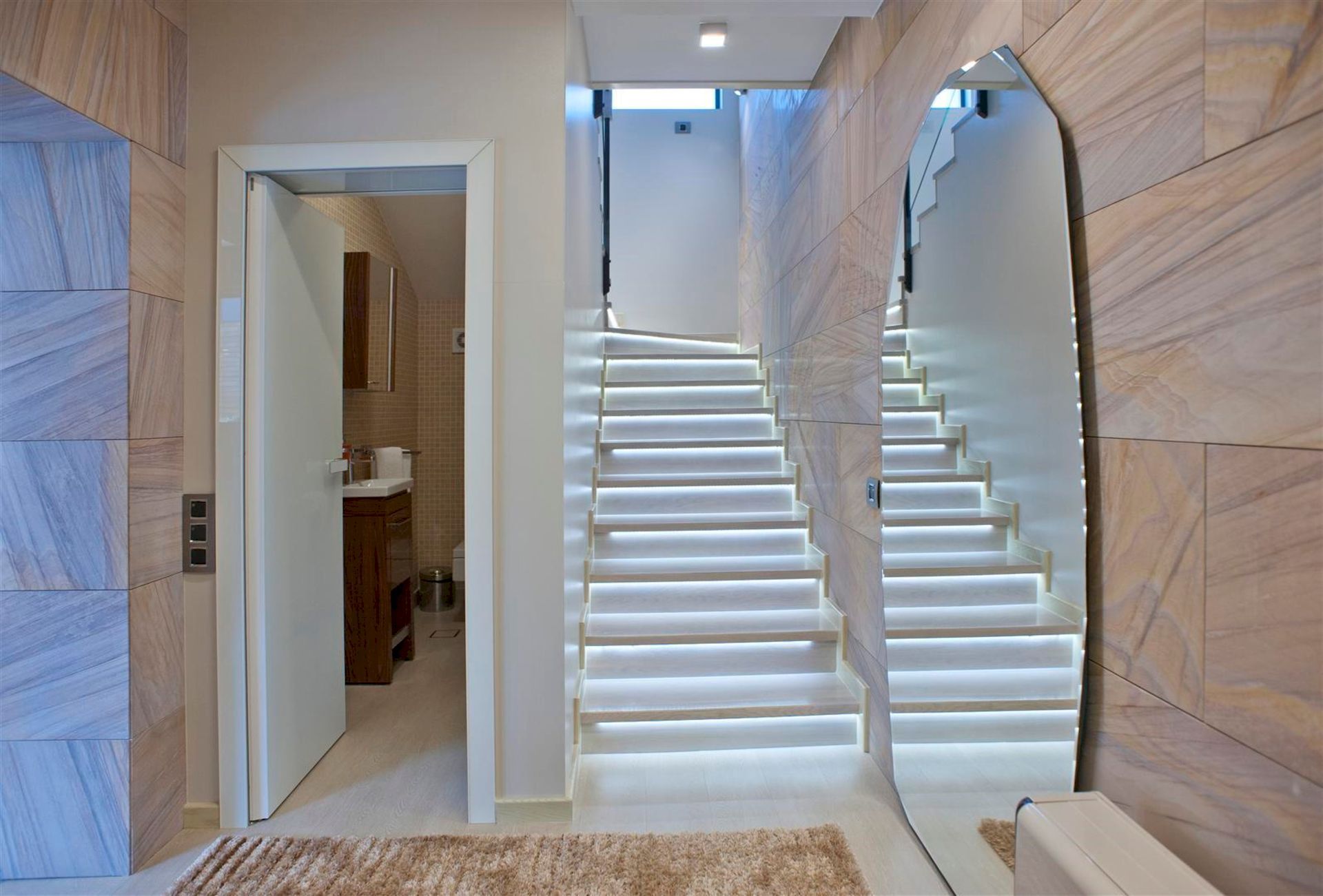 Escalier avec éclairage et miroir dans l’intérieur moderne d’une villa à Krašići, Monténégro, avec accès à la salle de bains.