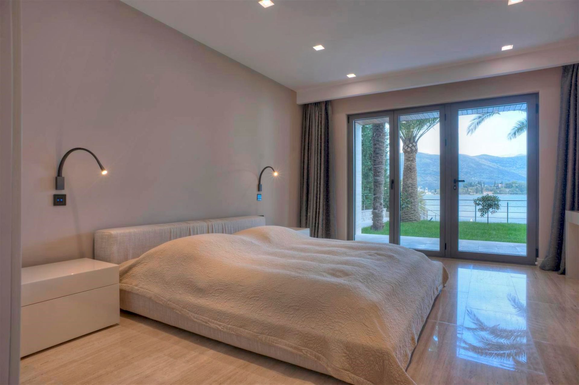 Chambre moderne dans une villa à Krašići, Monténégro, avec un lit double et une vue panoramique sur la mer et les montagnes.