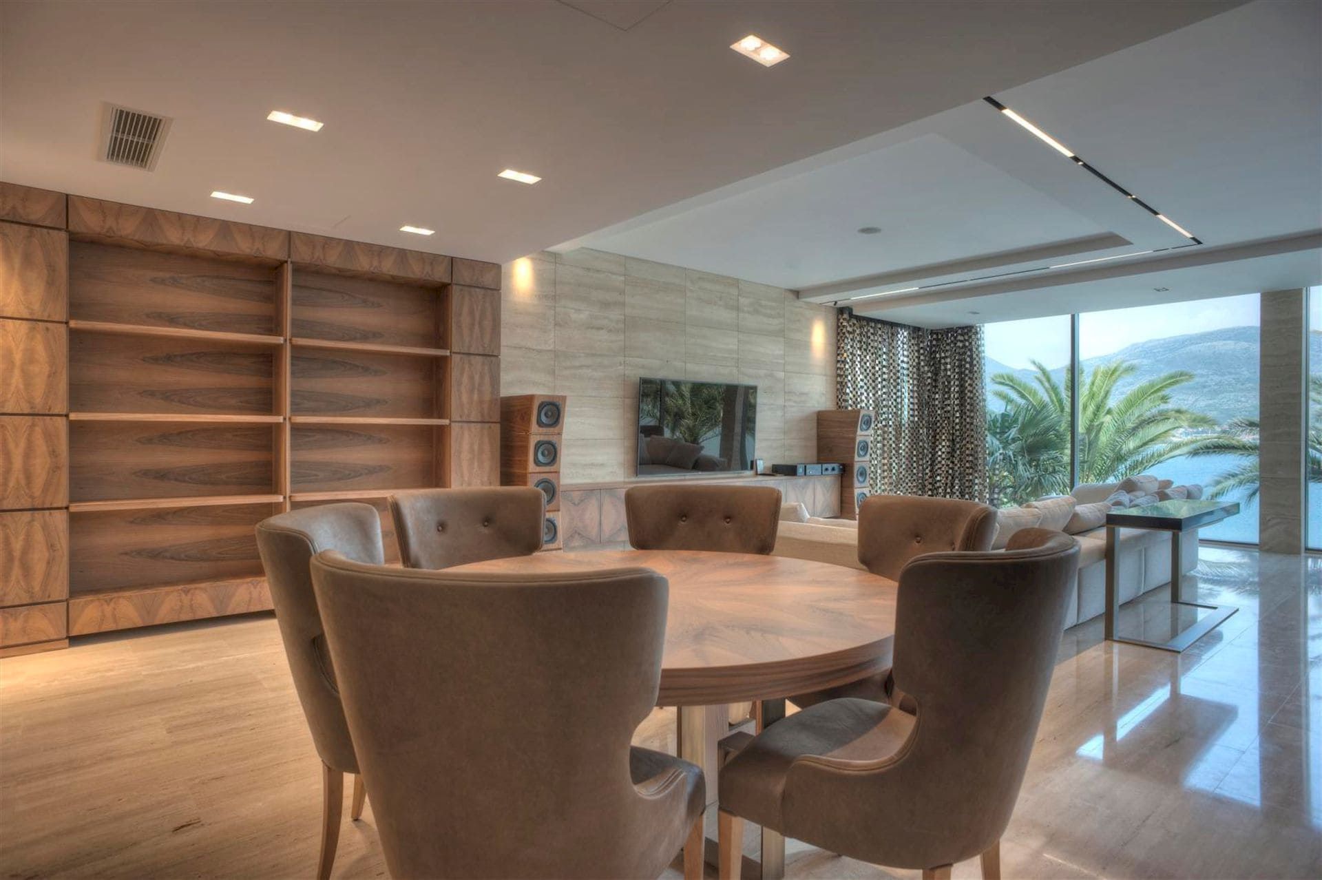 Salon avec coin repas dans une villa à Krašići, Monténégro : baies vitrées panoramiques, vue sur la mer et mobilier design.