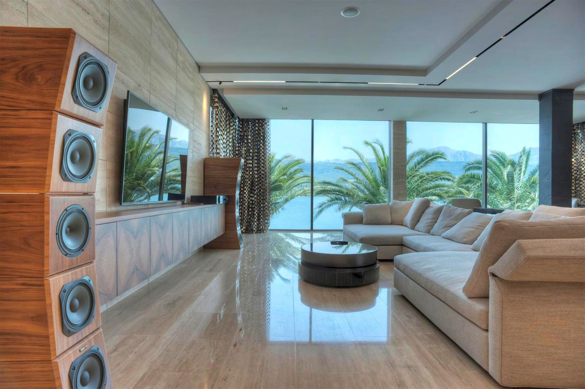 Salon d’une villa de luxe à Krašići, Monténégro : baies panoramiques avec vue sur la mer, mobilier design et système audio.