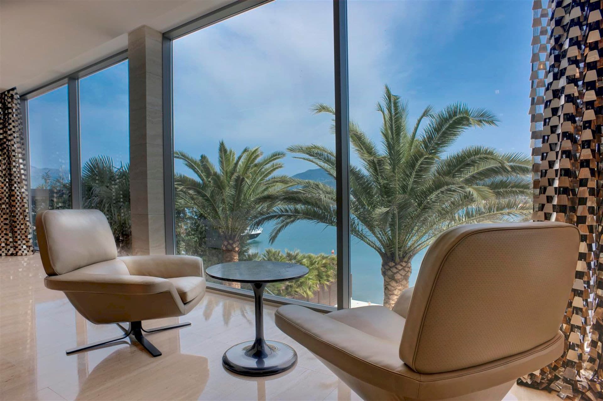 Salon avec baies vitrées panoramiques et vue sur la mer et les palmiers dans une villa de luxe, Krasići, Monténégro.