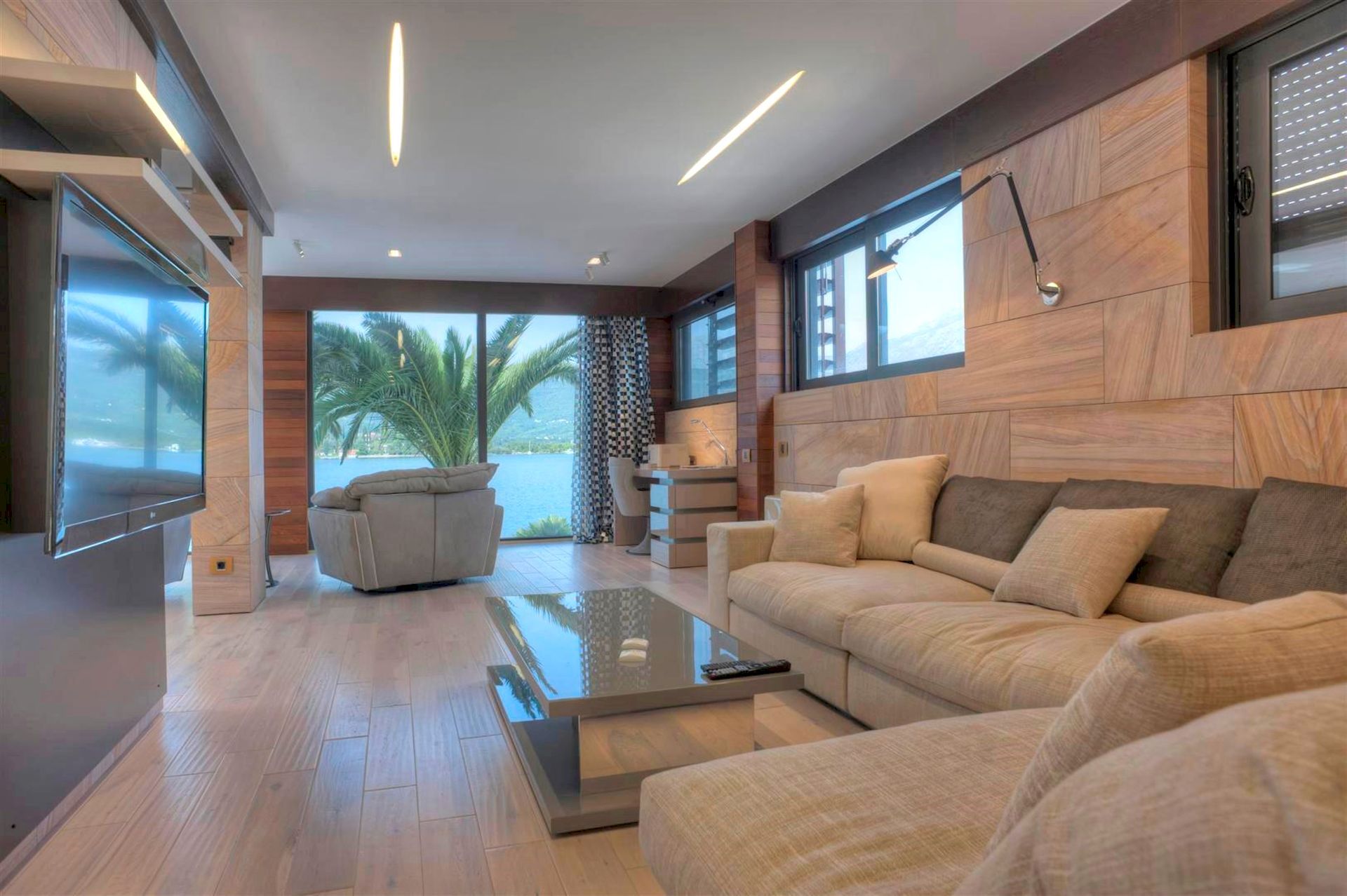 Salon moderne dans une villa à Krašići, Monténégro : vue panoramique sur la mer, finitions en bois et mobilier moelleux.