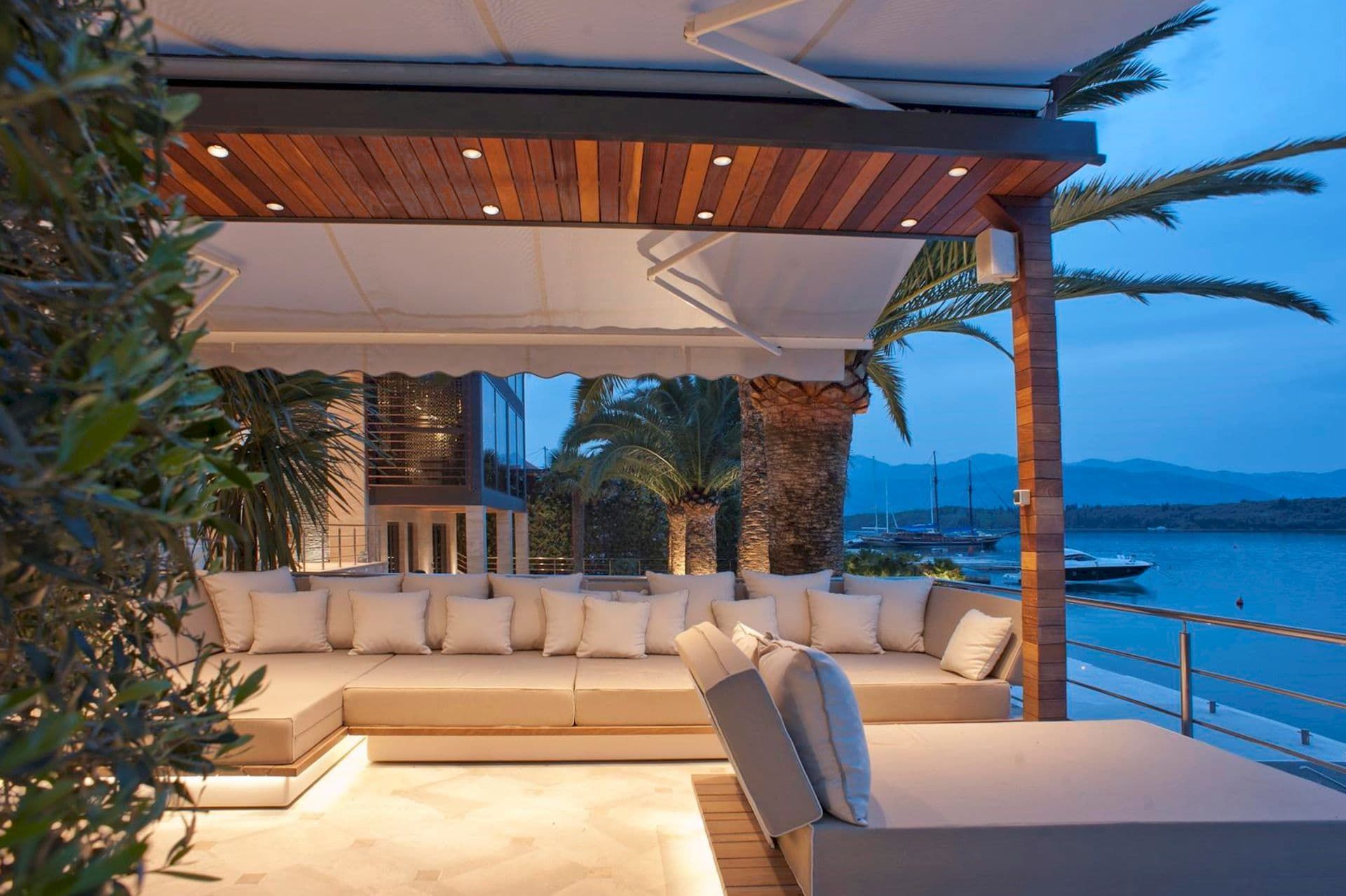 Terrasse de la villa à Krašići, Monténégro : mobilier moelleux, plafond en bois avec éclairage et vue sur la mer et les yachts.
