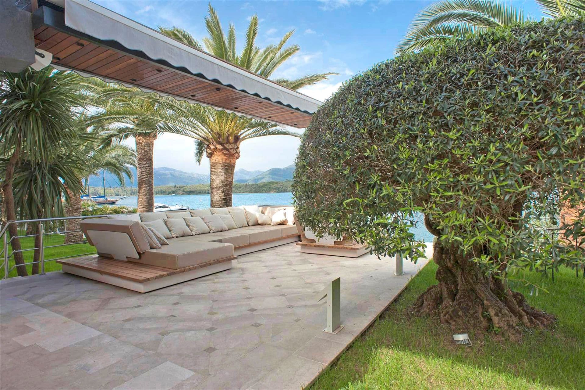 Terrasse de la villa à Krašići, Monténégro : mobilier d’extérieur, vue sur la mer, palmiers et olivier près de la maison.