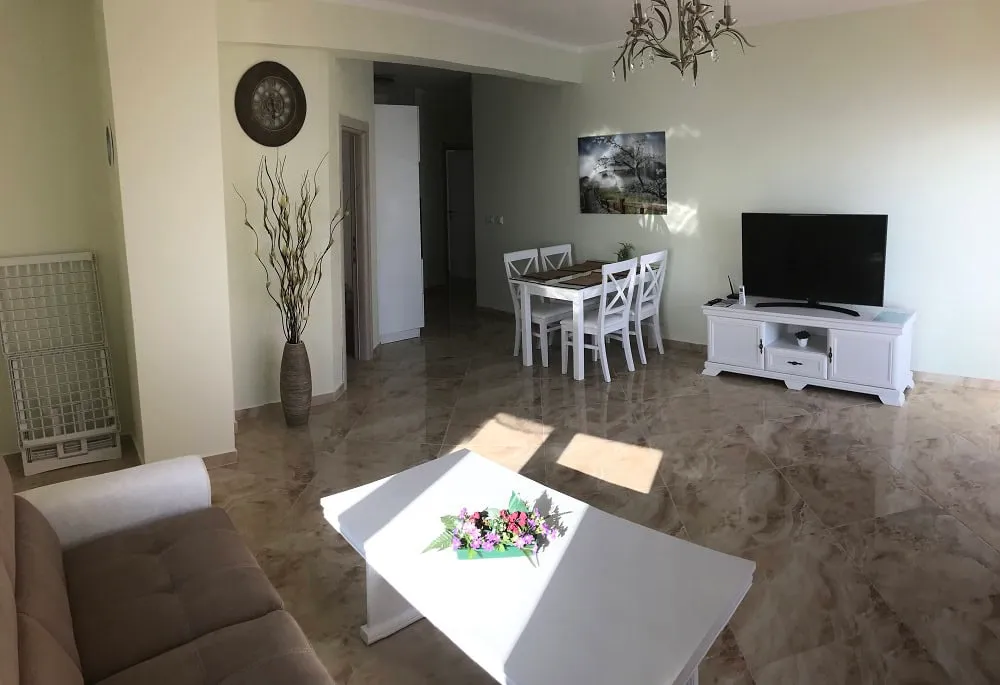 Bright living room with white furniture and marble flooring in an apartment for sale, Dobrota, Montenegro.