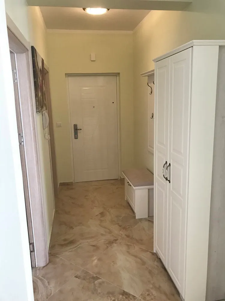 Bright entryway in an apartment, Dobri Vody, Montenegro: white wardrobe, bench, and tiled floor in the interior.