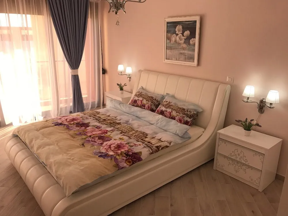Cozy bedroom with a white leather bed in an apartment, Dobri Vody, Montenegro: bright interior and panoramic window.