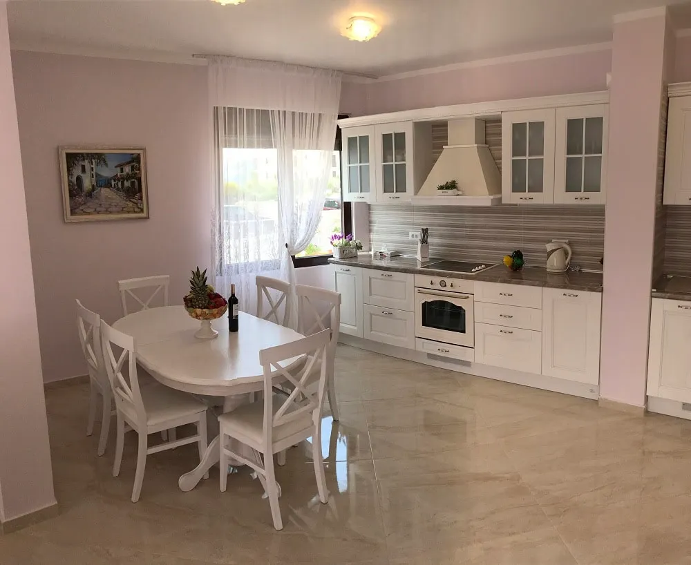 Bright kitchen-dining room with a white set in an apartment, Dobri Vody, Montenegro: dining area and modern appliances.