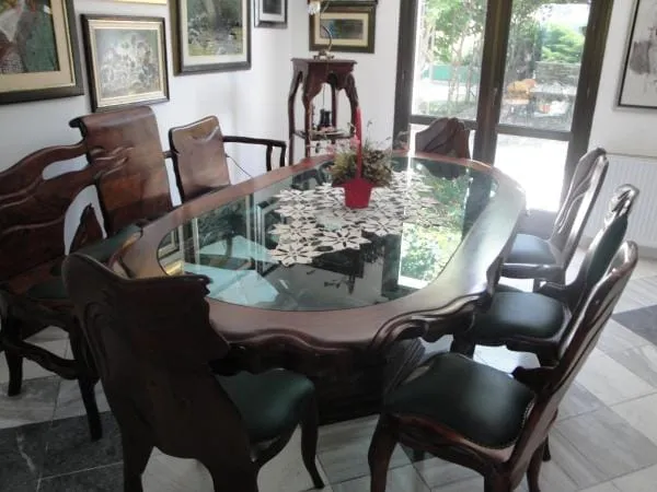 Dining area with a large oval glass-top table, wooden chairs, and various framed art pieces on the wall.