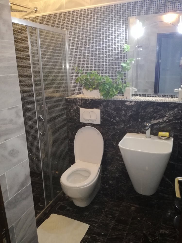 Karadağ, Bar’daki evde modern banyo: duş kabini, şık armatürler ve koyu mermer kaplama.
