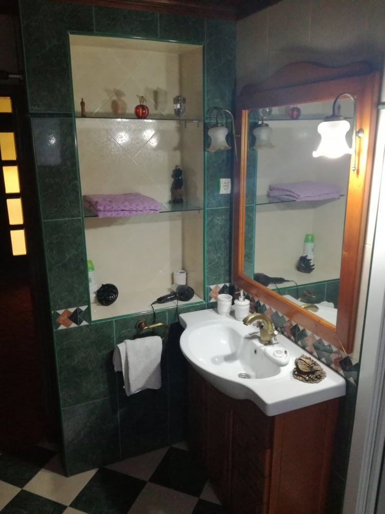 Karadağ, Bar’daki evde banyo: ahşap dolaplı lavabo, ayna ve fayans kaplamalı gömme raflar.