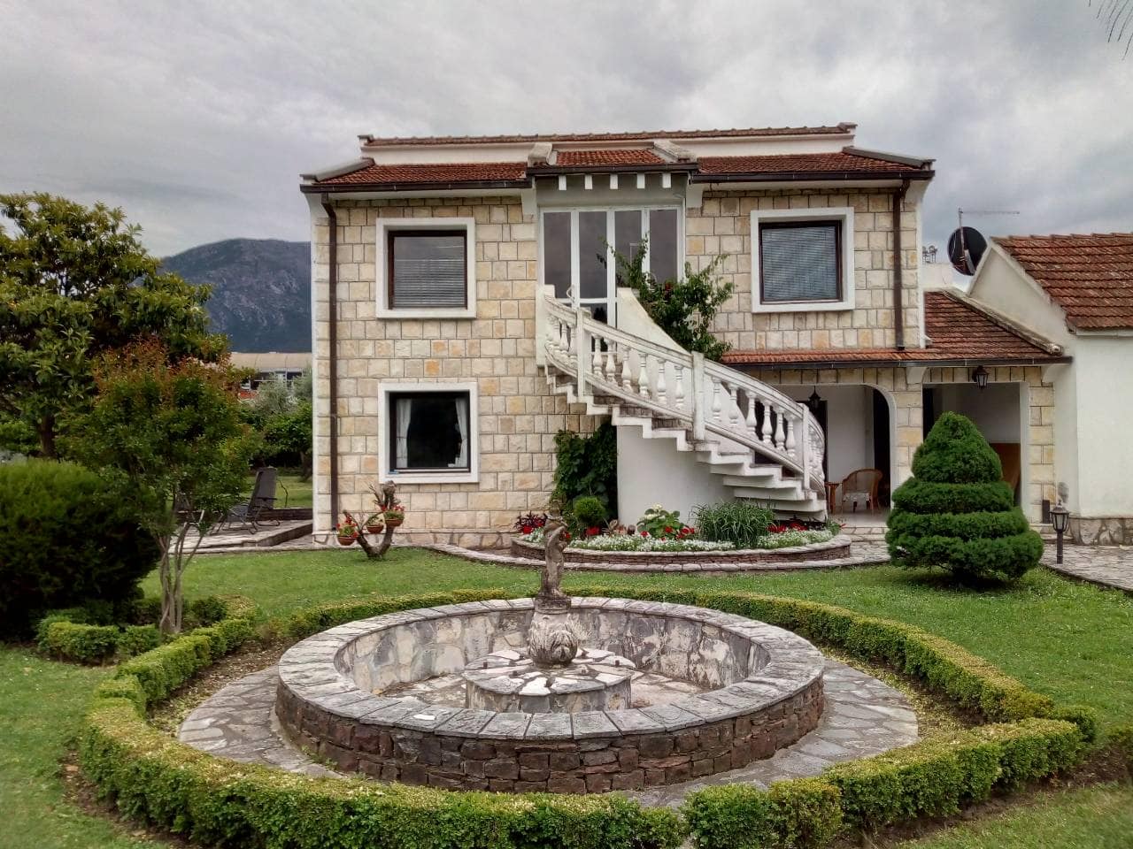 Karadağ, Bar’da dış spiral merdivenli, bahçeli ve arsasında yuvarlak bir çeşmesi olan iki katlı taş ev.