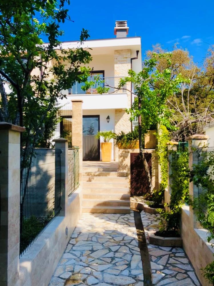 Karadağ, Dobra Voda’da modern villa: taş kaplamalı cephe, teras ve düzenlenmiş ev girişi.