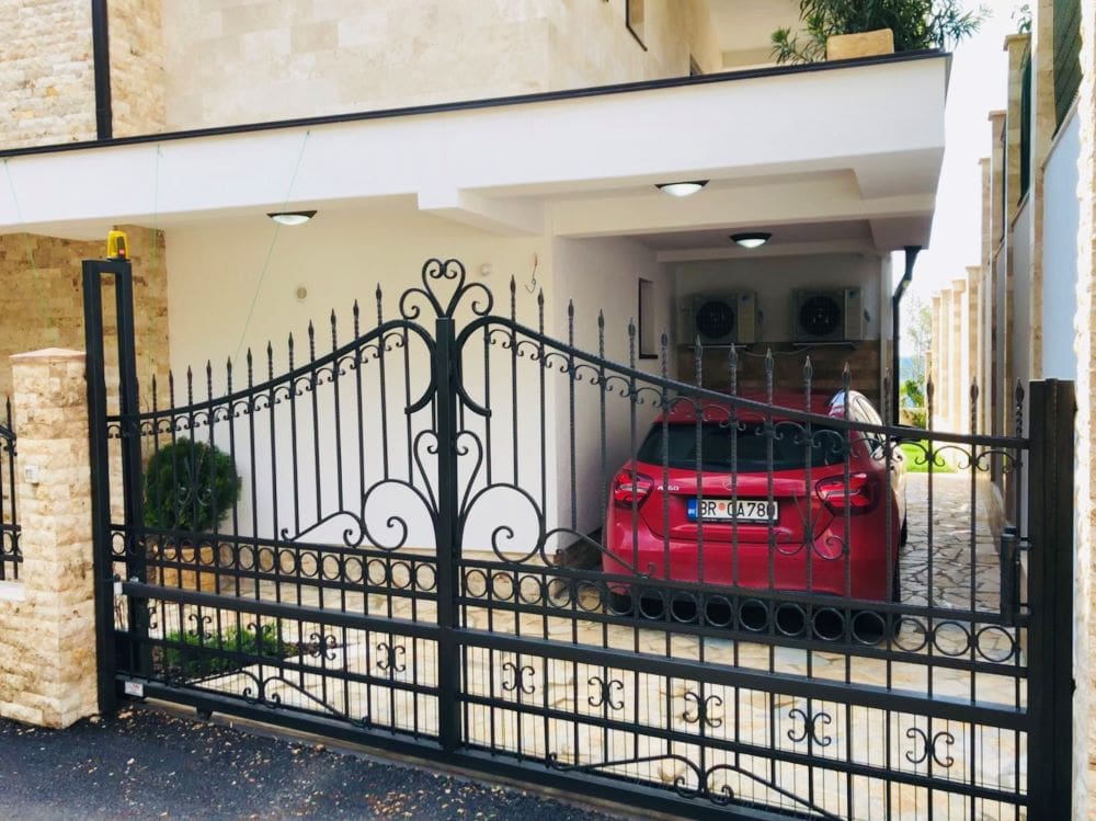 Karadağ, Dobri Vody’de özel ev: ferforje kapılar, araç için kapalı otopark ve taş kaplama cephe.