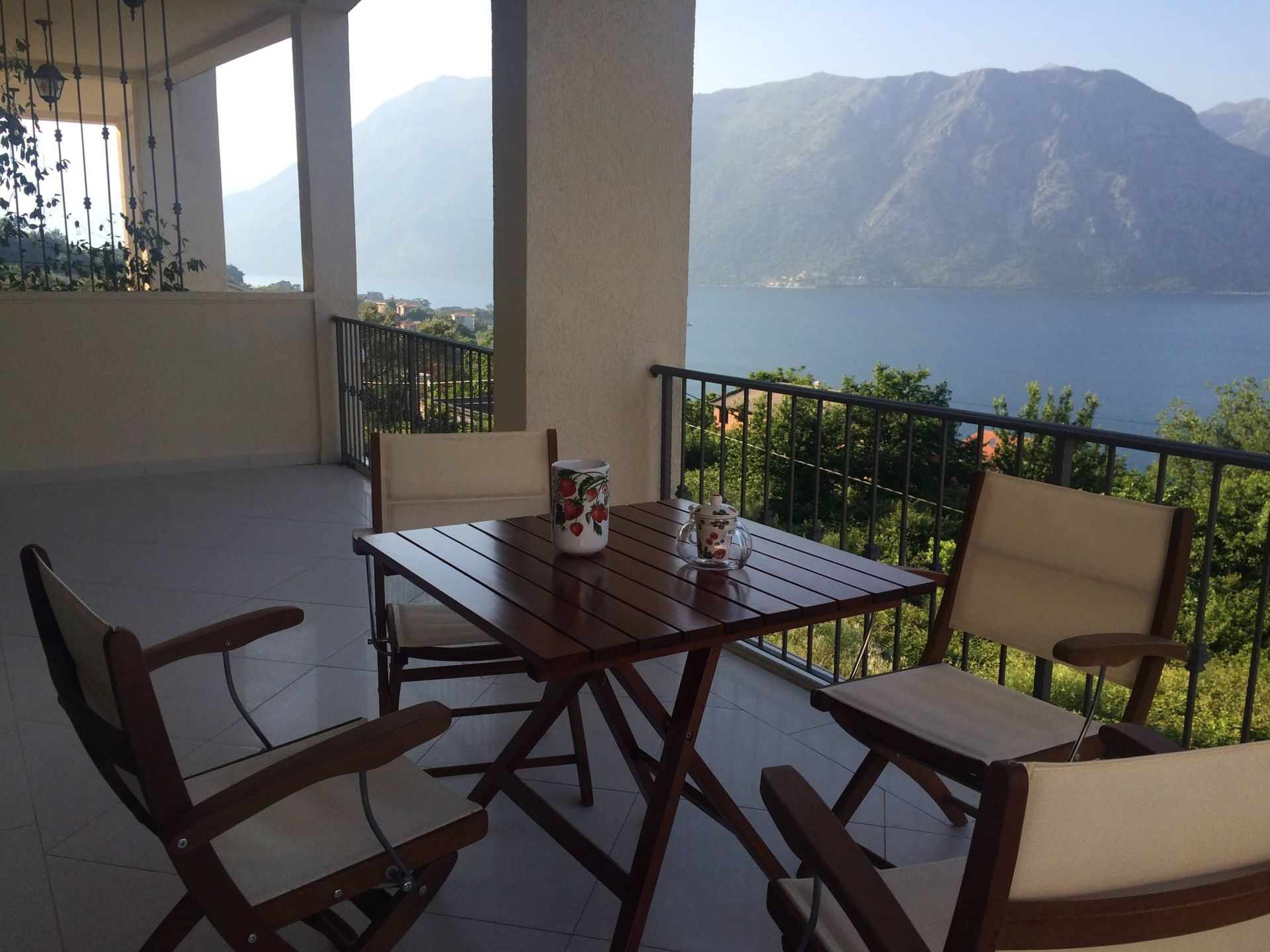 Kotor Körfezi ve dağların panoramik manzarasına sahip ahşap mobilyalı teras, Prčanj’deki daire, Karadağ.