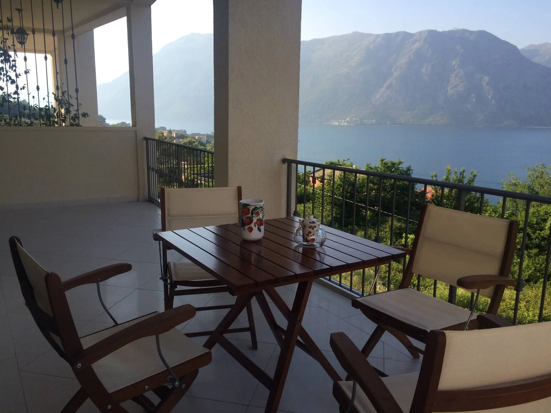 Kotor Körfezi ve dağların panoramik manzarasına sahip ahşap mobilyalı teras, Prčanj’deki daire, Karadağ.