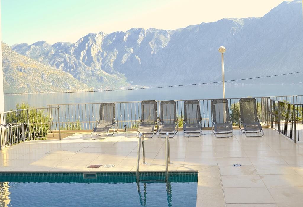 Şezlonglu havuz ve Kotor Körfezi ile dağların panoramik manzarası, Prčanj, Karadağ.