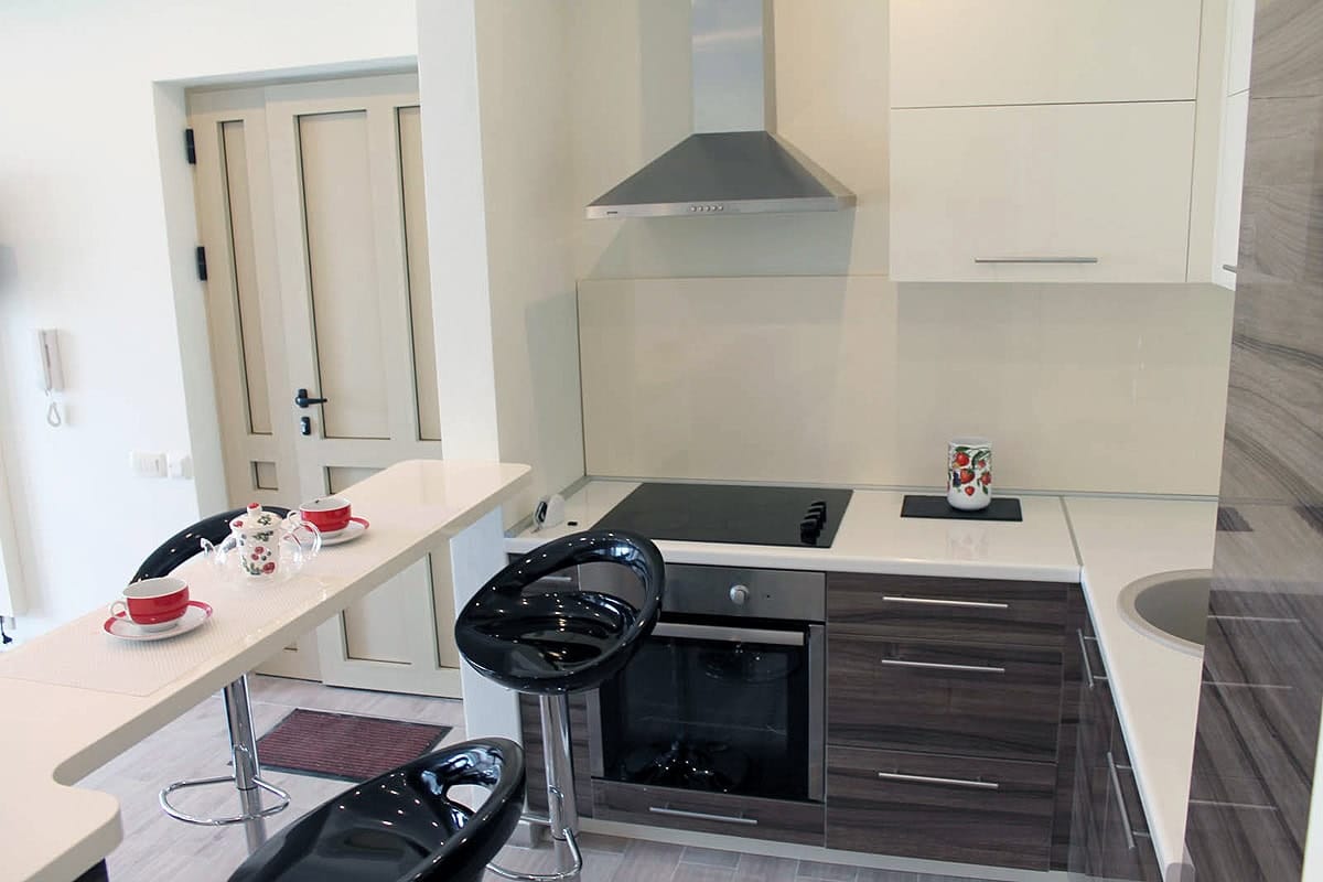 Karadağ, Prčanj’de satılık dairede bar tezgahlı ve siyah sandalyeli modern mutfak.