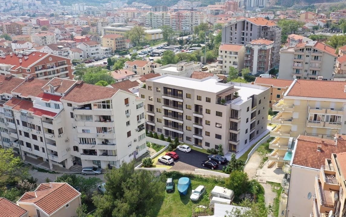 Luftaufnahme eines modernen Wohnkomplexes in Budva, Montenegro, mit eigenem Parkplatz und städtischer Bebauung.