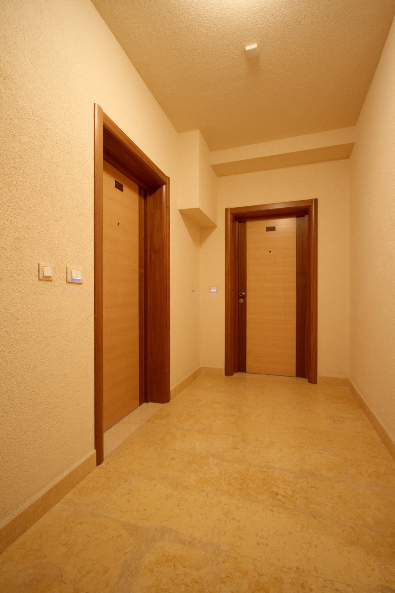Heller Flur in einer Wohnung in Bečići, Montenegro: hochwertige Wandverkleidung, Innentüren und Steinboden.