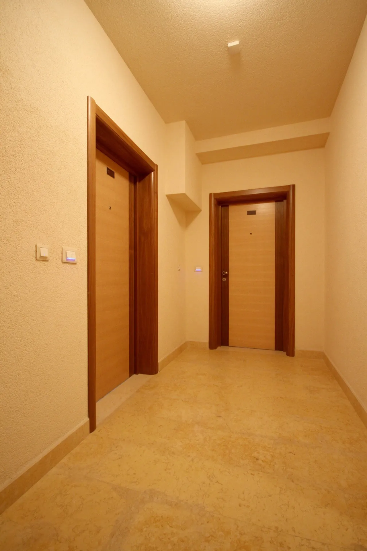 Heller Flur in einer Wohnung in Bečići, Montenegro: hochwertige Wandverkleidung, Innentüren und Steinboden.
