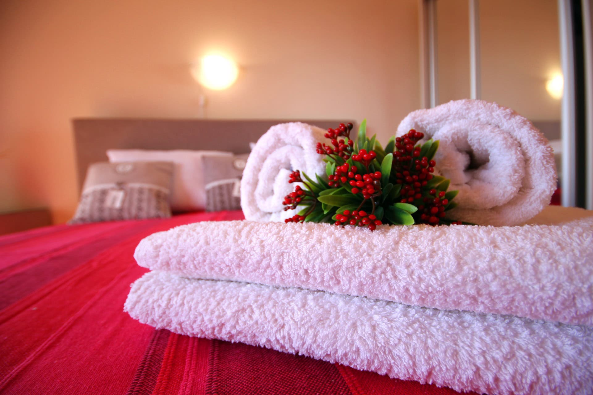 Gemütliches Schlafzimmer in einer Wohnung in Bečići, Montenegro: Doppelbett mit roter Tagesdecke und weißen Handtüchern.