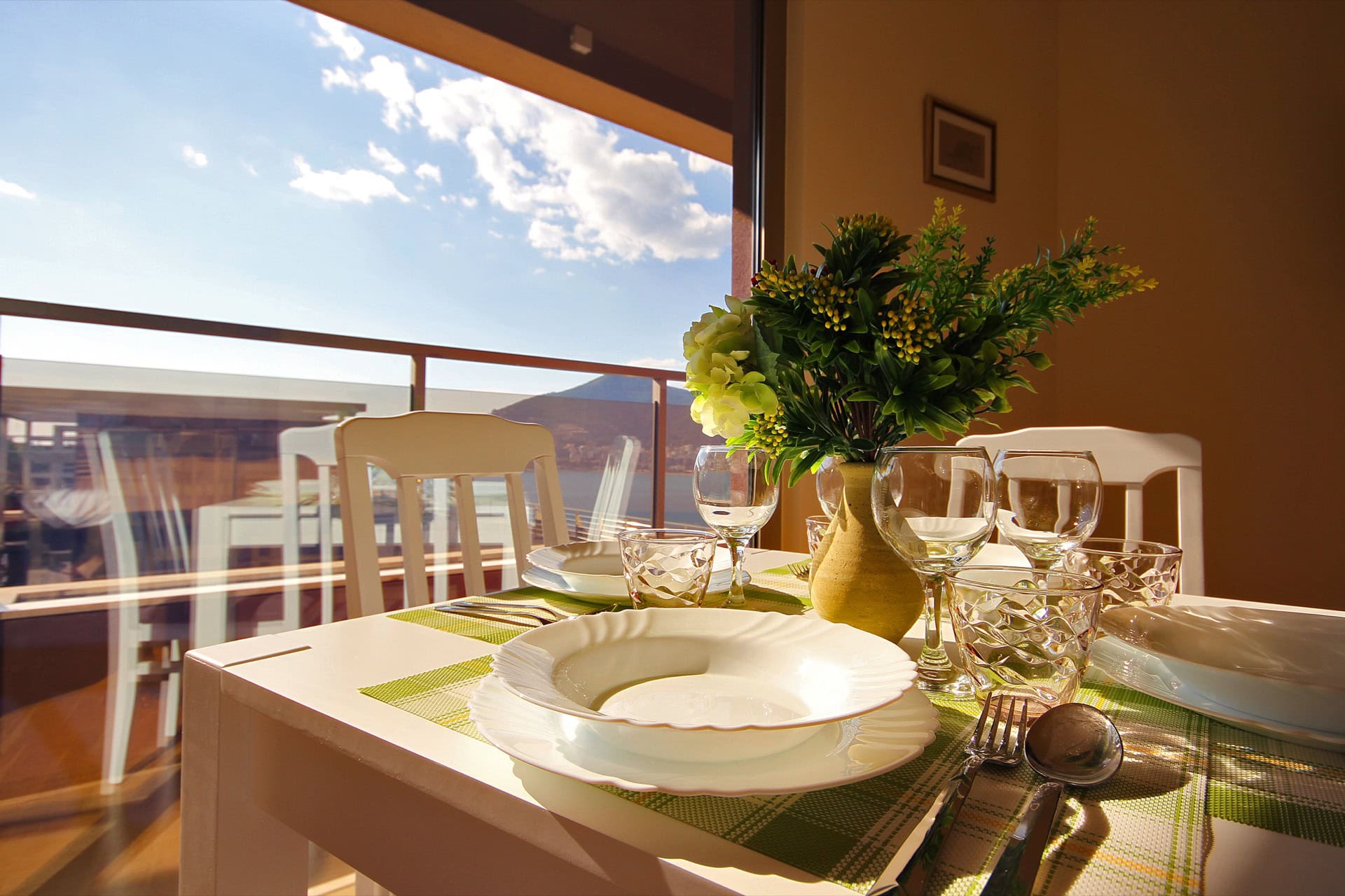 Tischgedeck im Wohnzimmer einer Wohnung in Bečići, Montenegro, mit Panoramablick auf Meer und Berge durch den Balkon.