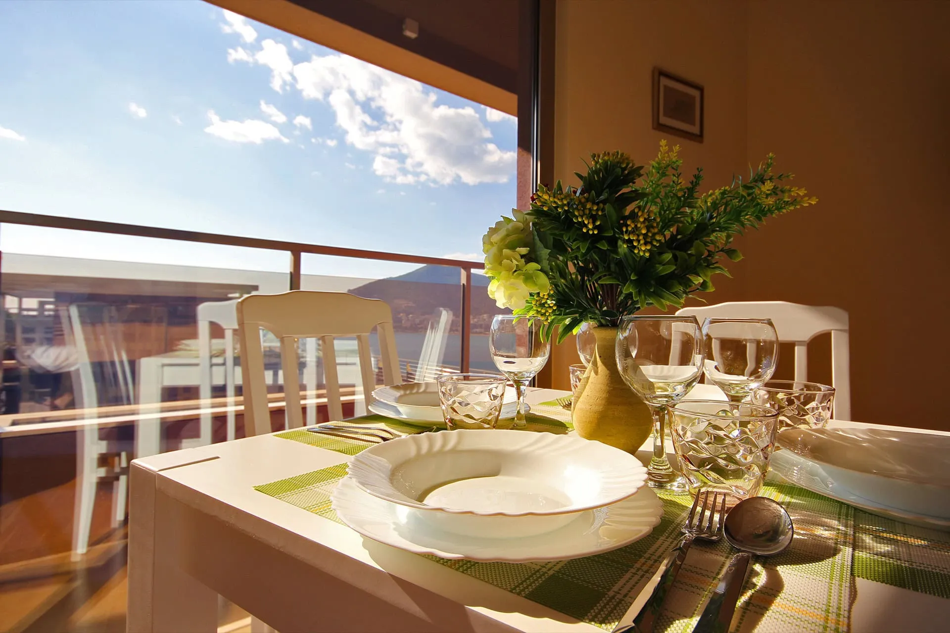 Tischgedeck im Wohnzimmer einer Wohnung in Bečići, Montenegro, mit Panoramablick auf Meer und Berge durch den Balkon.