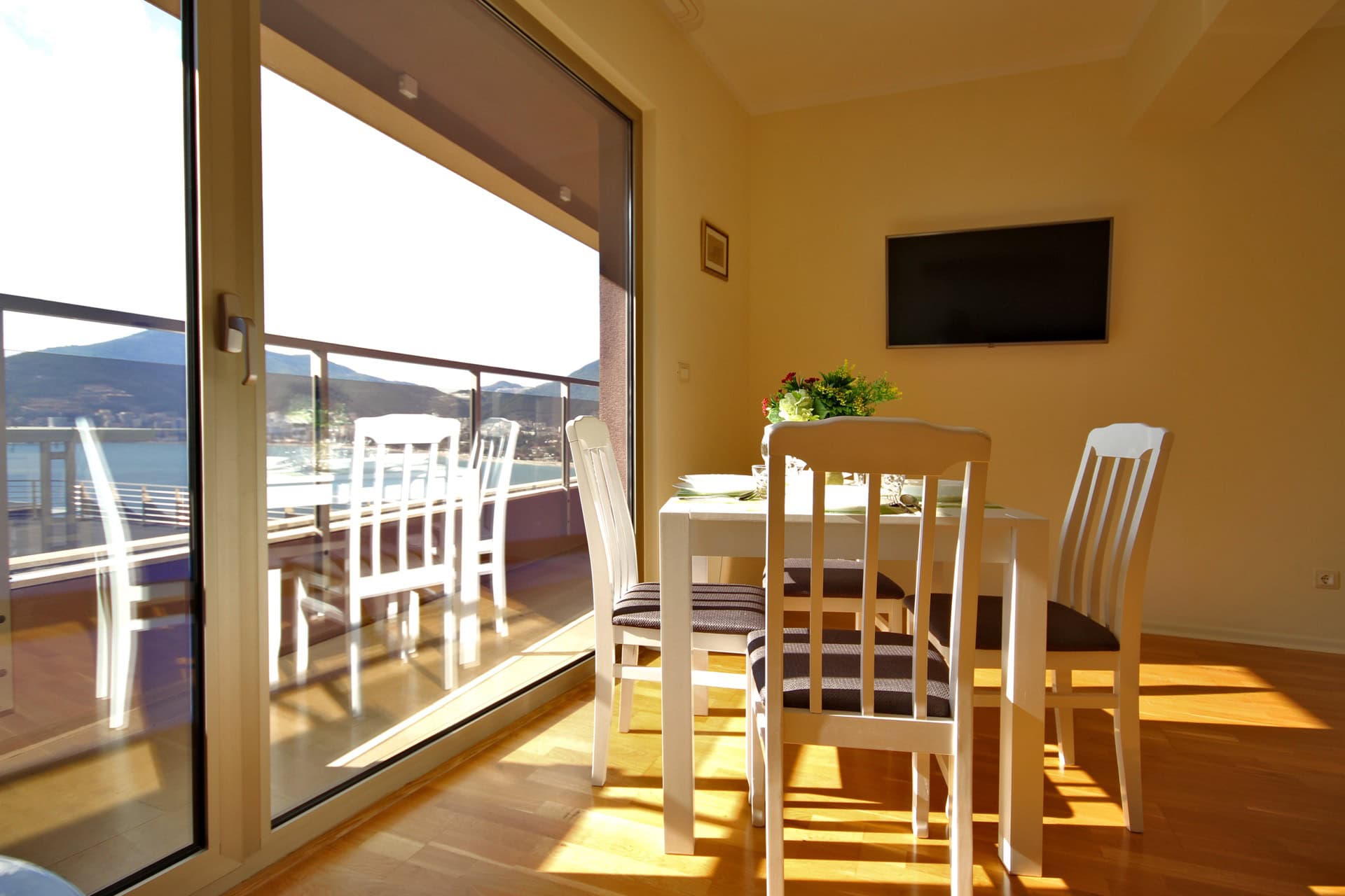 Wohnzimmer mit Essbereich in einer Wohnung in Bečići, Montenegro: Panoramafenster, Meerblick und Zugang zur Terrasse.