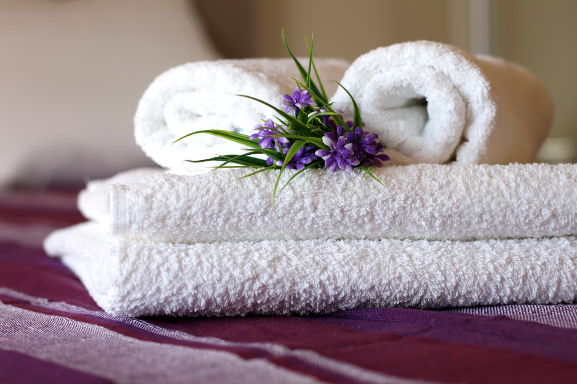 Weiße Frotteehandtücher mit Blumen auf dem Bett im Schlafzimmer der Apartments in Bečići, Montenegro.