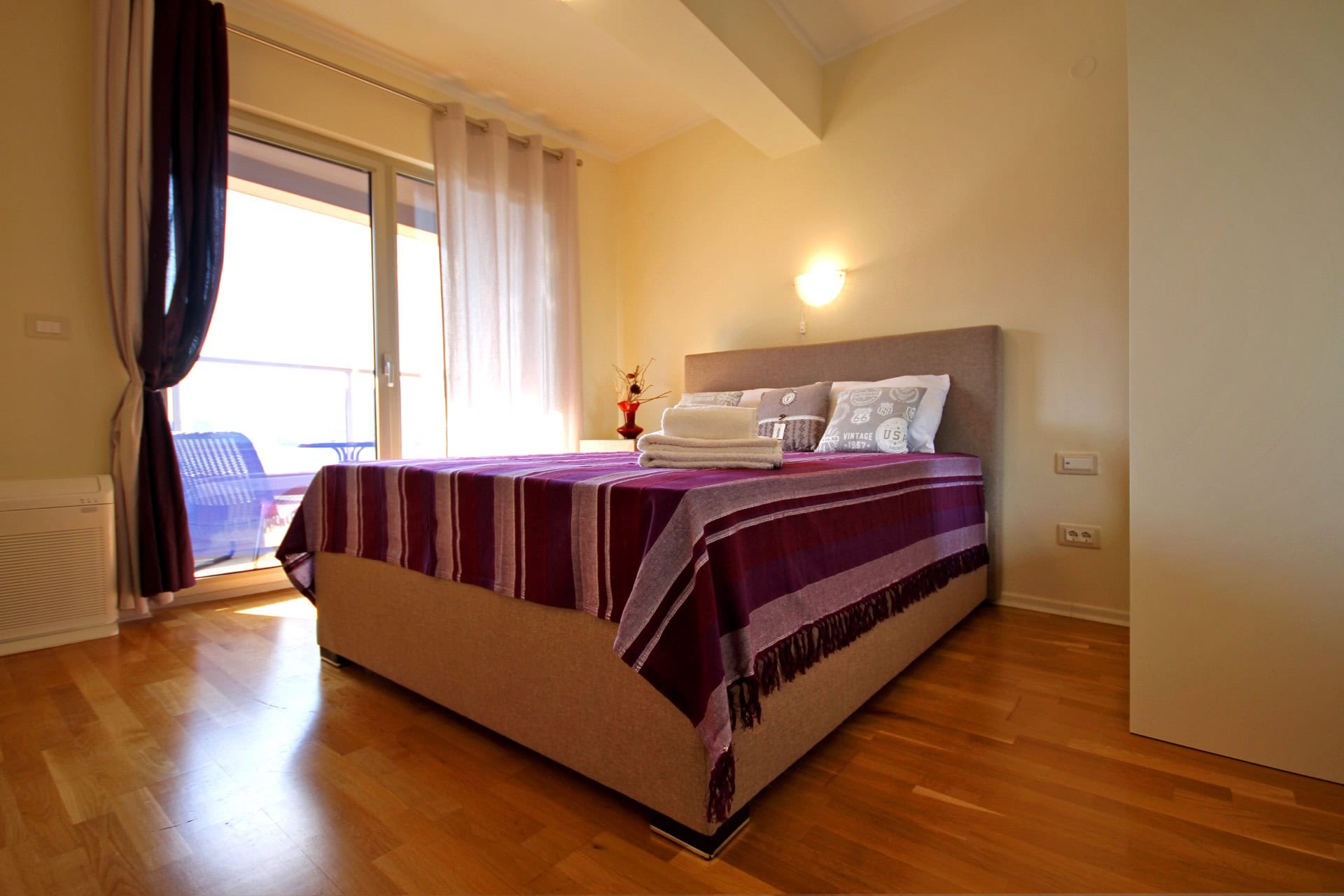 Gemütliches Schlafzimmer mit Doppelbett und Zugang zum Balkon in einer Wohnung, Bečići, Montenegro.