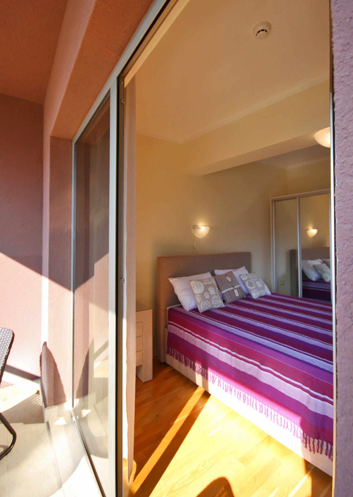 Schlafzimmer mit Doppelbett und Zugang zum Balkon in einer Wohnung in Bečići, Montenegro. Parkett, Einbauschrank, gemütliches Interieur.