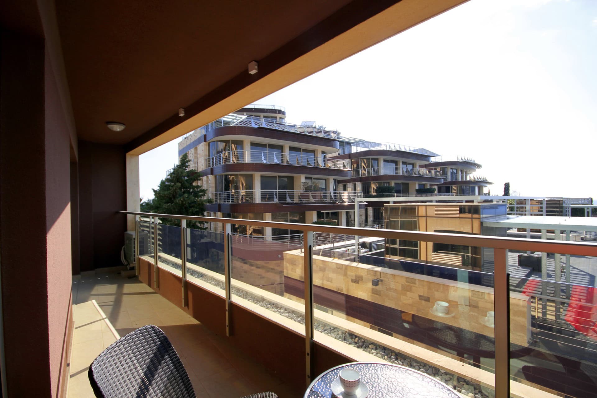 Geräumiger Balkon mit Rattanmöbeln und Blick auf moderne Wohnanlagen in Bečići, Montenegro.