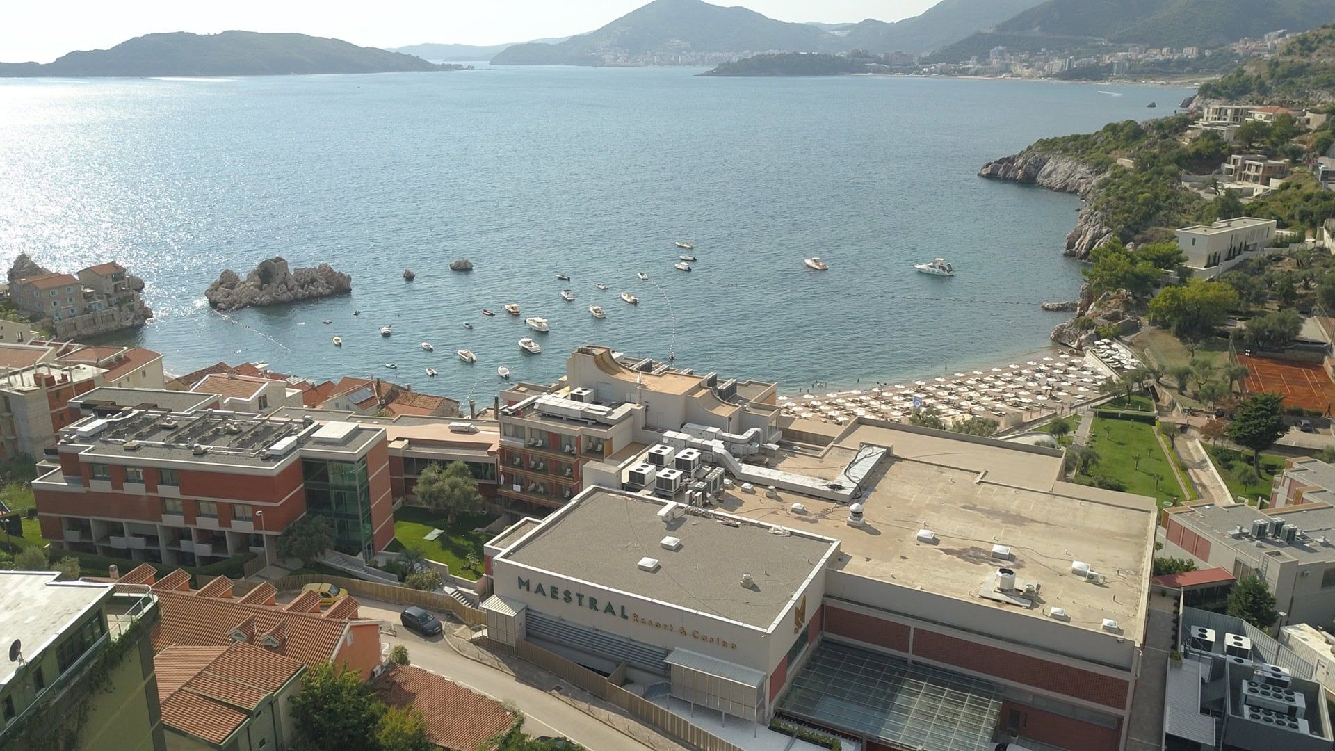 Panoramic sea view and the Maestral Hotel in Pržno, Montenegro: beach, yachts, and mountains from the penthouse terrace.