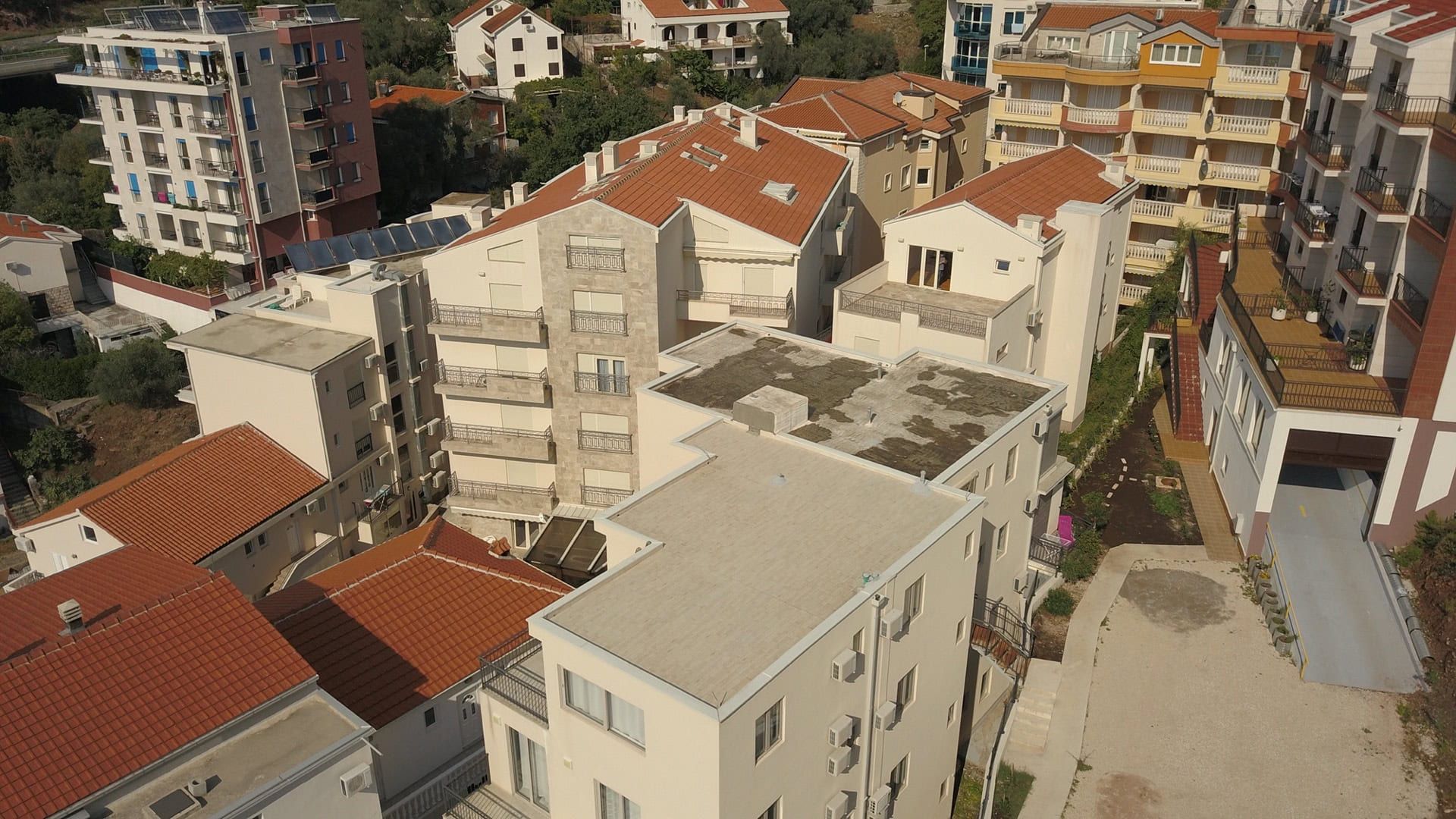 Aerial view of a residential complex in Pržno, Montenegro: modern apartment buildings with terraces and tiled roofs.