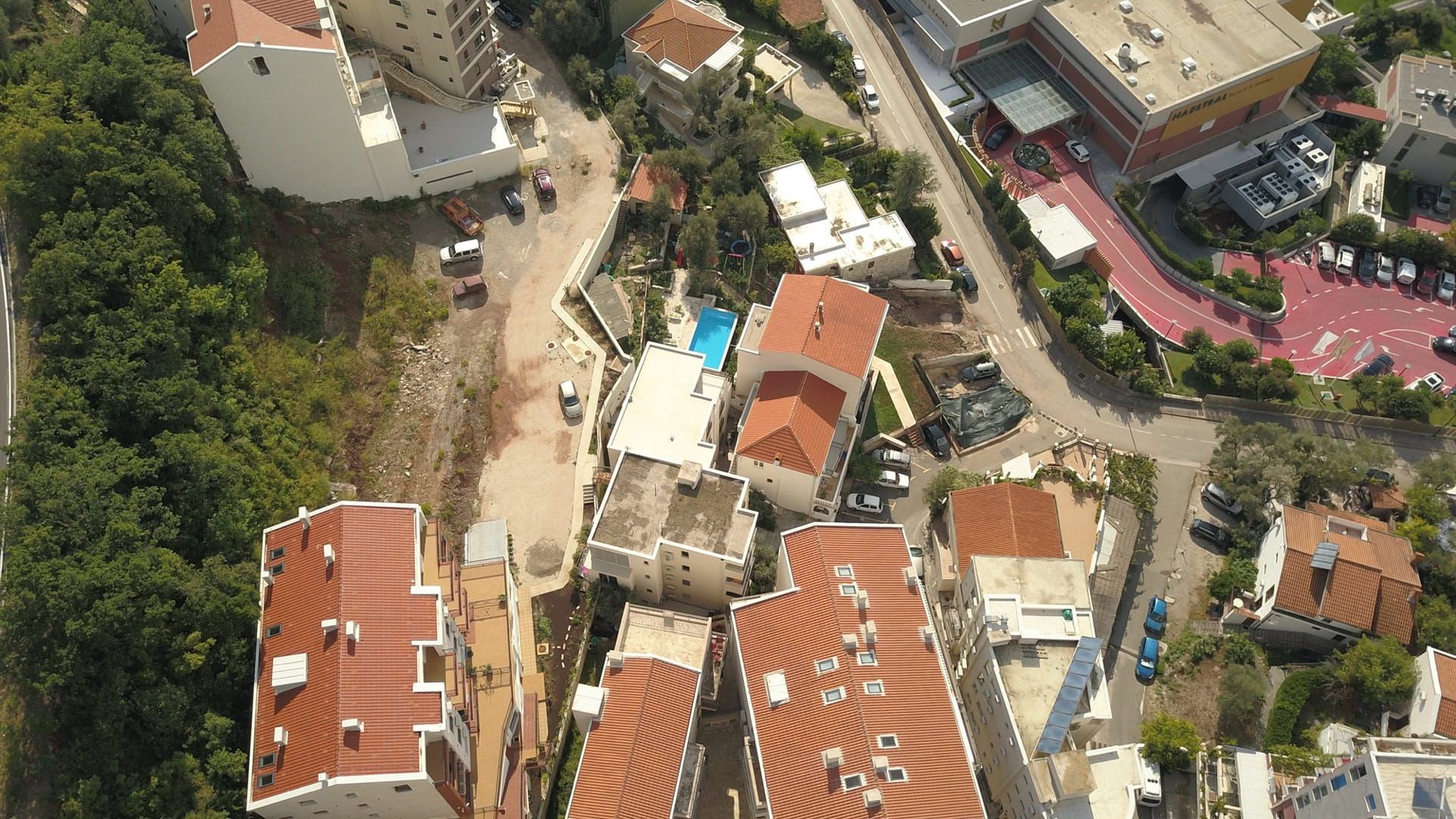 Aerial view of a residential complex in Pržno, Montenegro: tiled roofs, a pool, and neighborhood infrastructure.