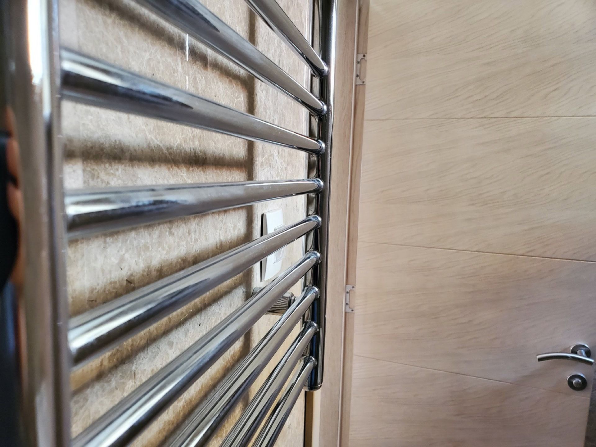 Chrome towel warmer in the penthouse bathroom in Pržno, Montenegro, with modern wall and door finishes.