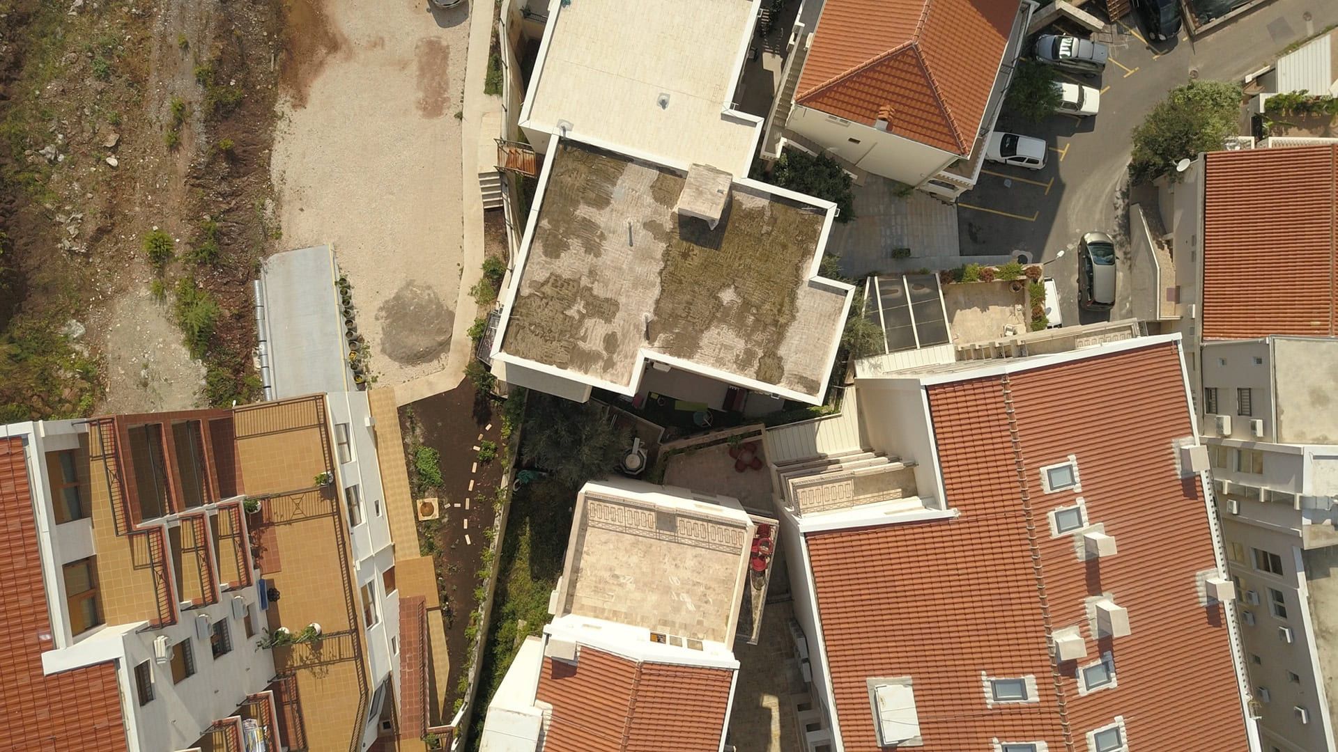 Aerial view of a residential complex with tiled roofs in Pržno, Montenegro: building architecture and surrounding grounds.