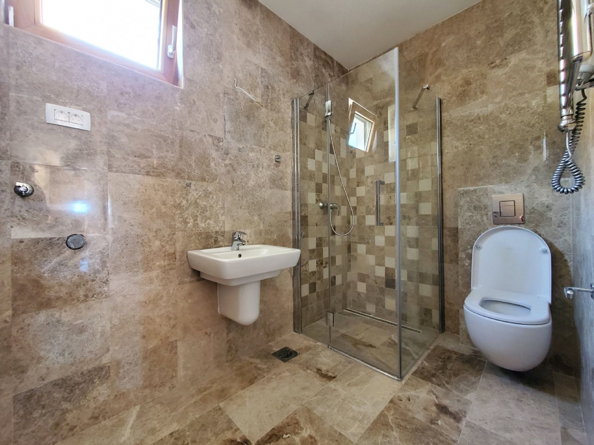 Modern bathroom in a penthouse in Pržno, Montenegro: shower cabin, white sanitary ware, and stone finishes.