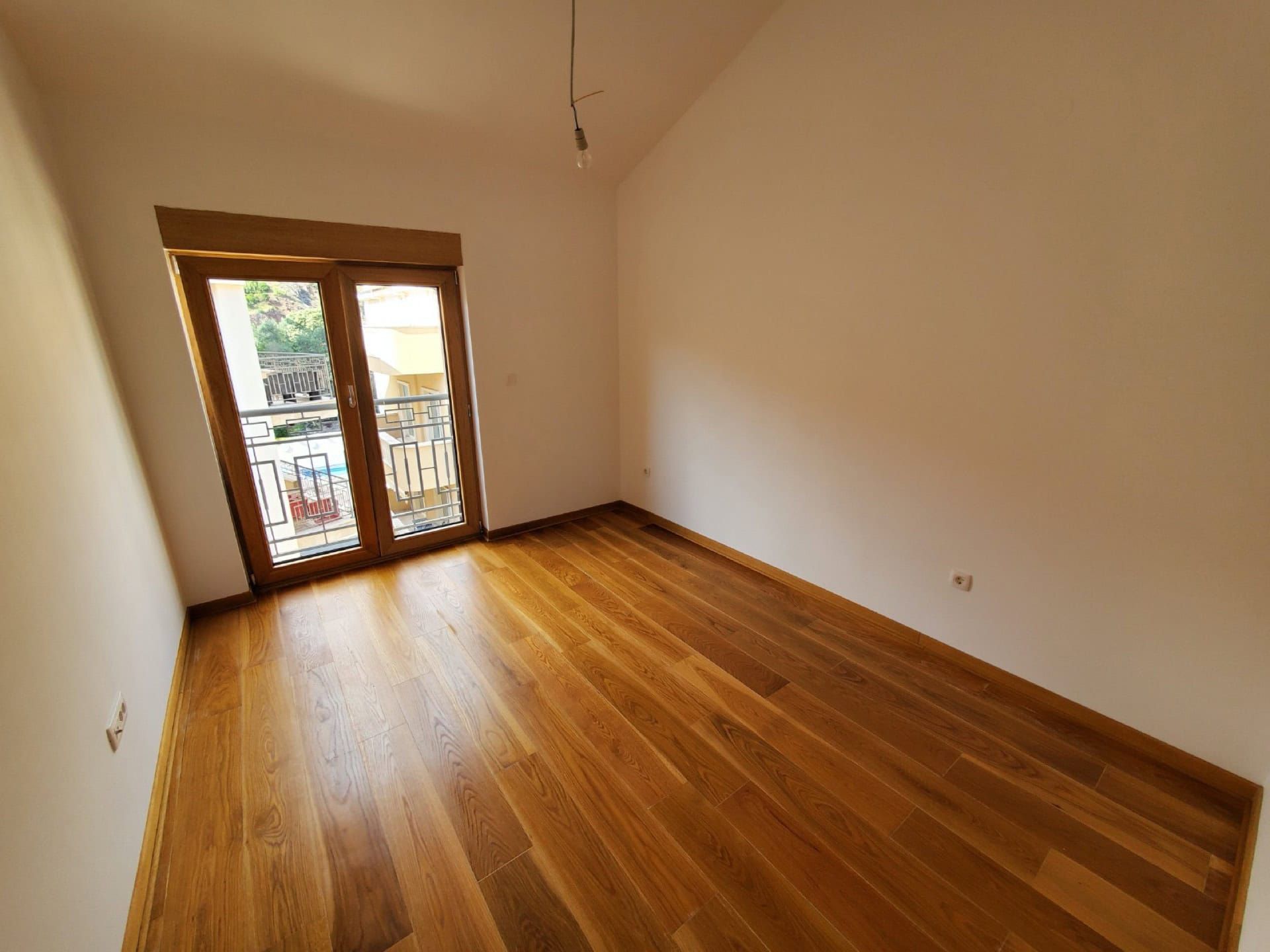 Bright bedroom with wooden flooring and access to the balcony in a penthouse, Pržno, Montenegro.