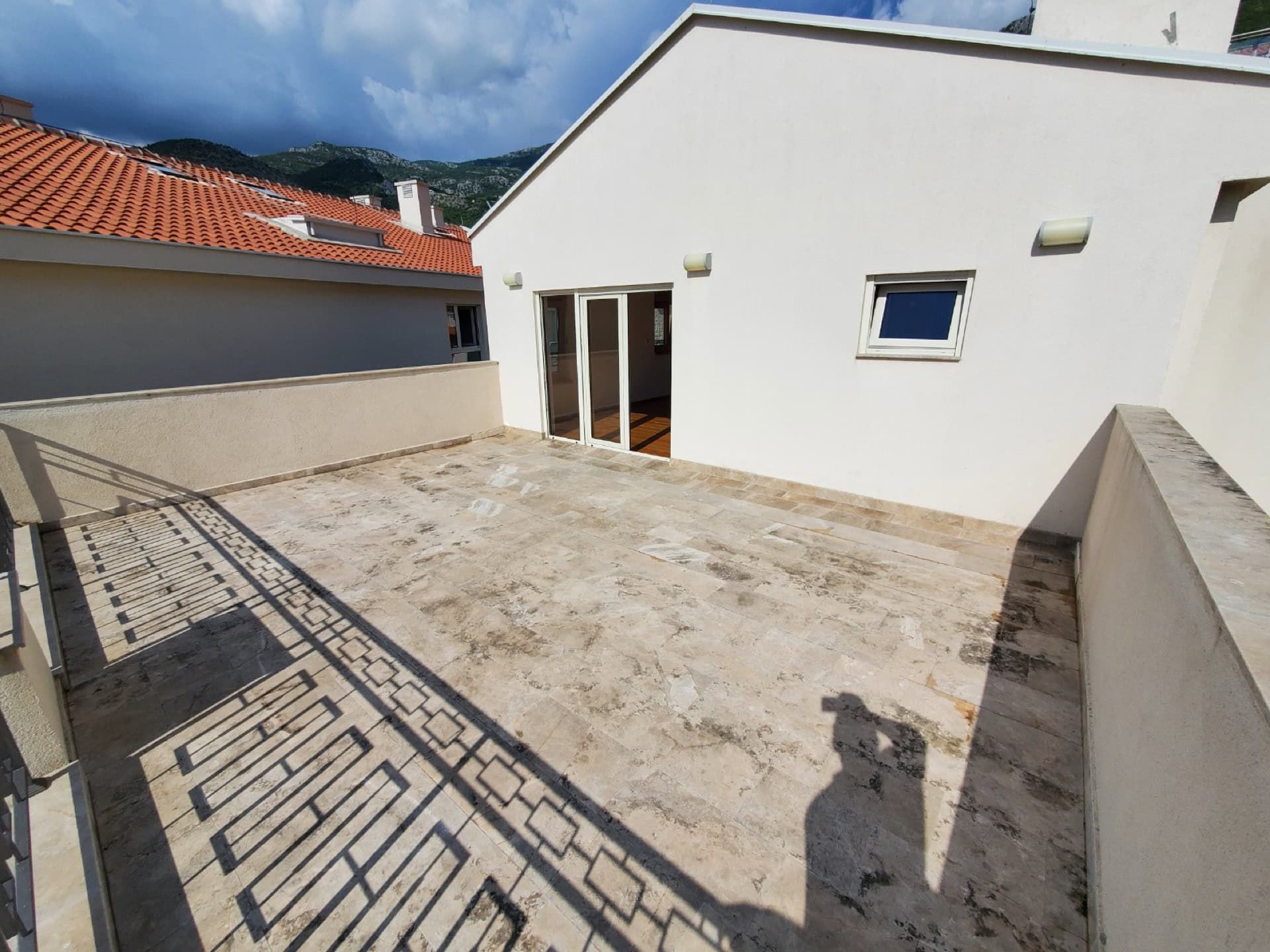 Spacious open penthouse terrace in Pržno, Montenegro, with stone flooring and mountain views.